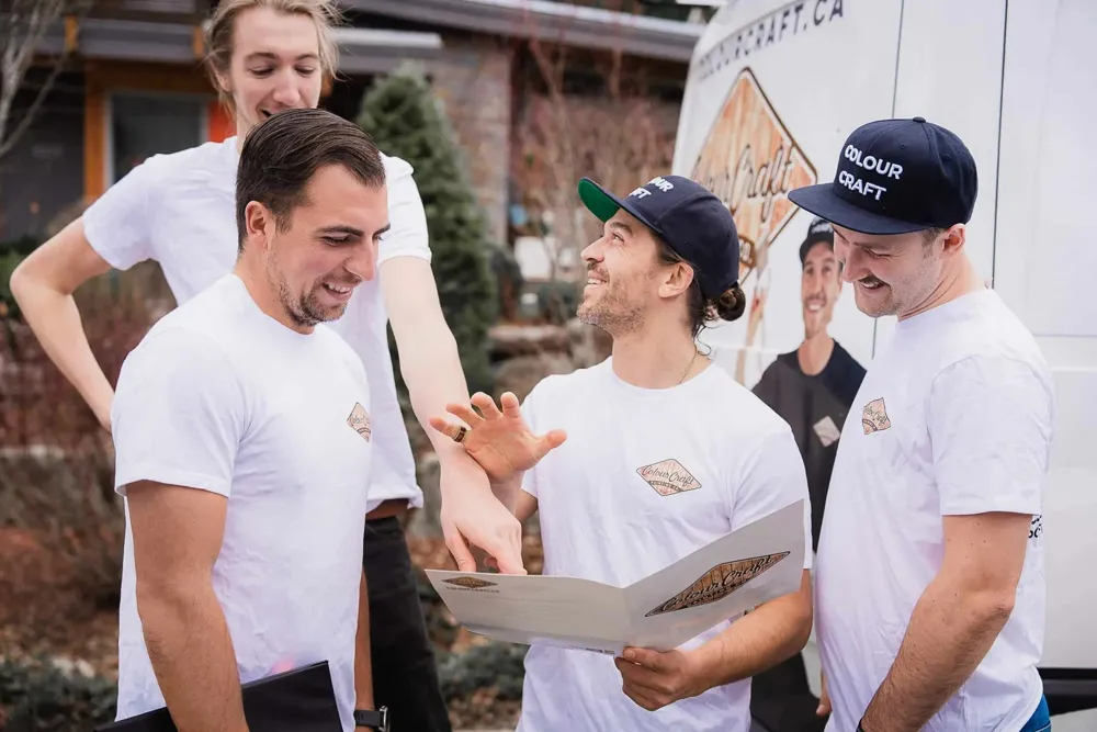 Colour Craft crew reviewing the project plan together beside the branded van