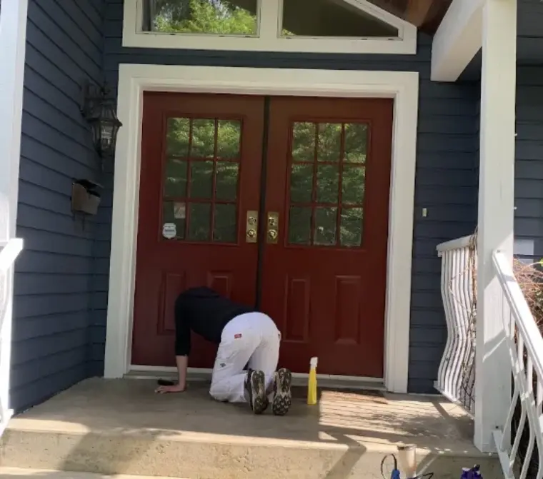 Painter finishing a bold red double front door, exterior door painting by Colour Craft Painting