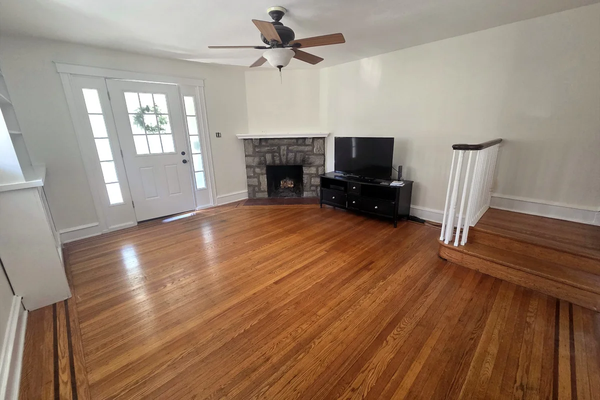 Living room walls painted white after an interior repaint by Colour Craft Painting, with a stone fireplace and oak floors