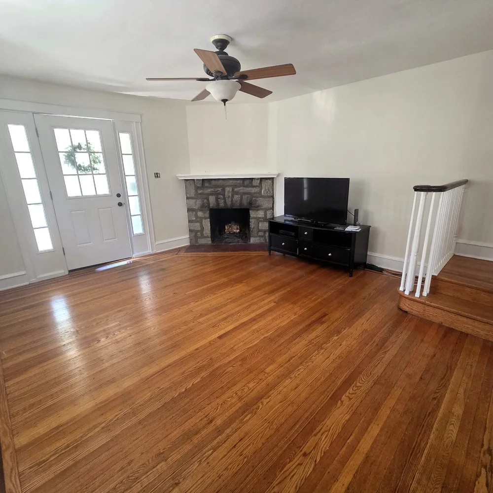 Living room with a stone fireplace and oak floors after an interior repaint by Colour Craft Painting