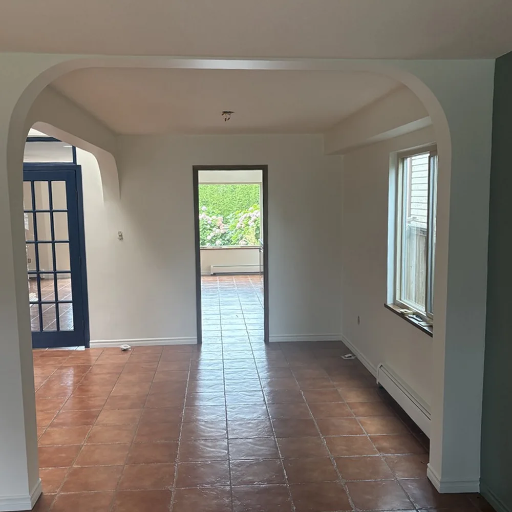 Arched living room after a whole-home interior repaint by Colour Craft Painting, white walls and trim with navy French doors